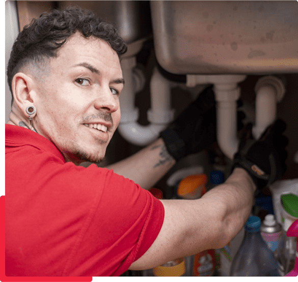 Plumber fixing a burst pipe in a residential bathroom